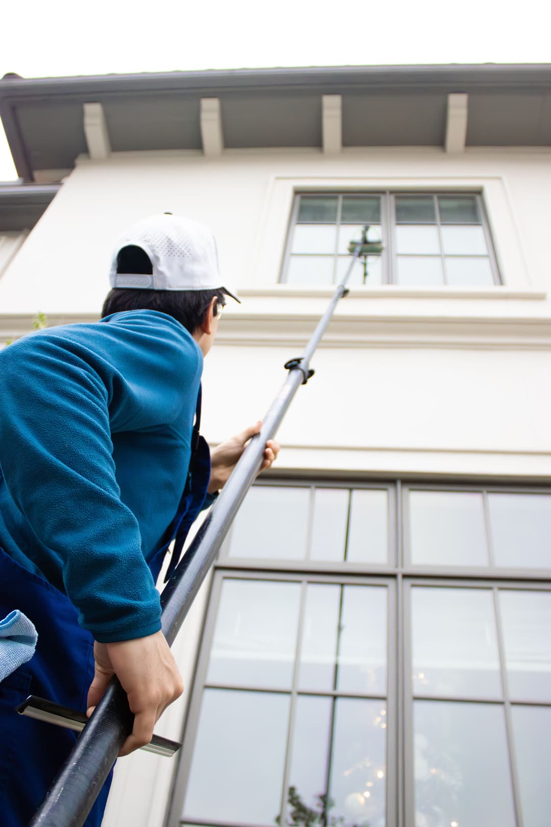 Person cleaning a window with a pole, showcasing professional window cleaning services.